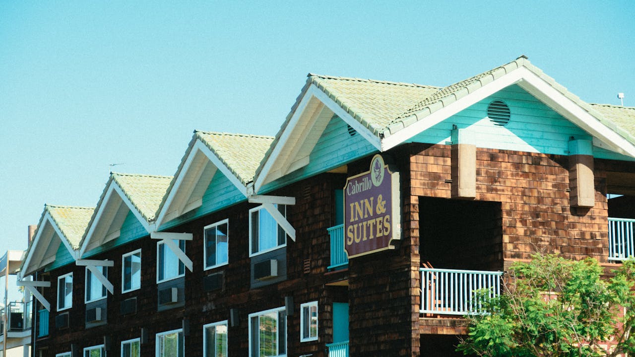 A picturesque wooden facade of Cabrillo Inn & Suites against a clear blue sky.