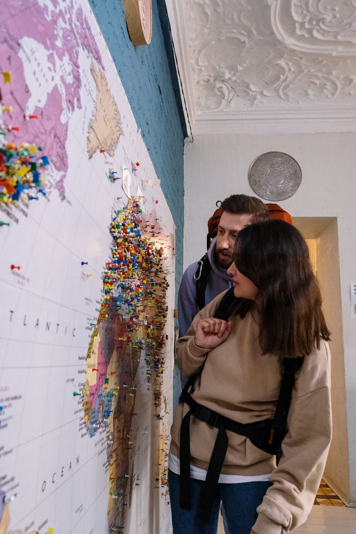 Couple exploring world map with pins, highlighting travel plans in cozy indoor setting.